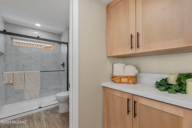 bathroom featuring hardwood / wood-style flooring, a shower with door, and toilet