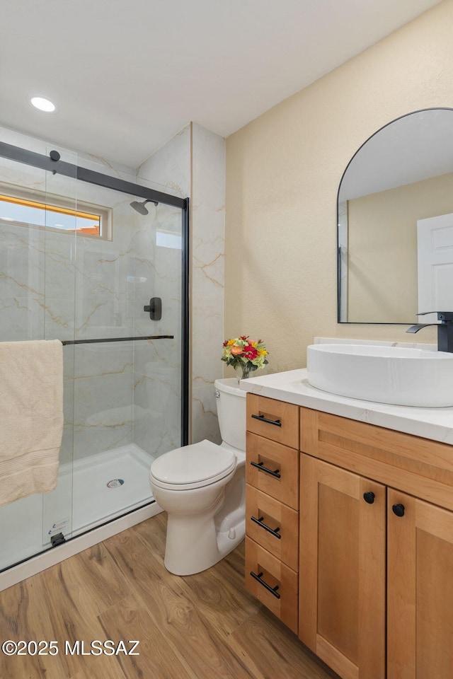 bathroom featuring hardwood / wood-style flooring, walk in shower, vanity, and toilet