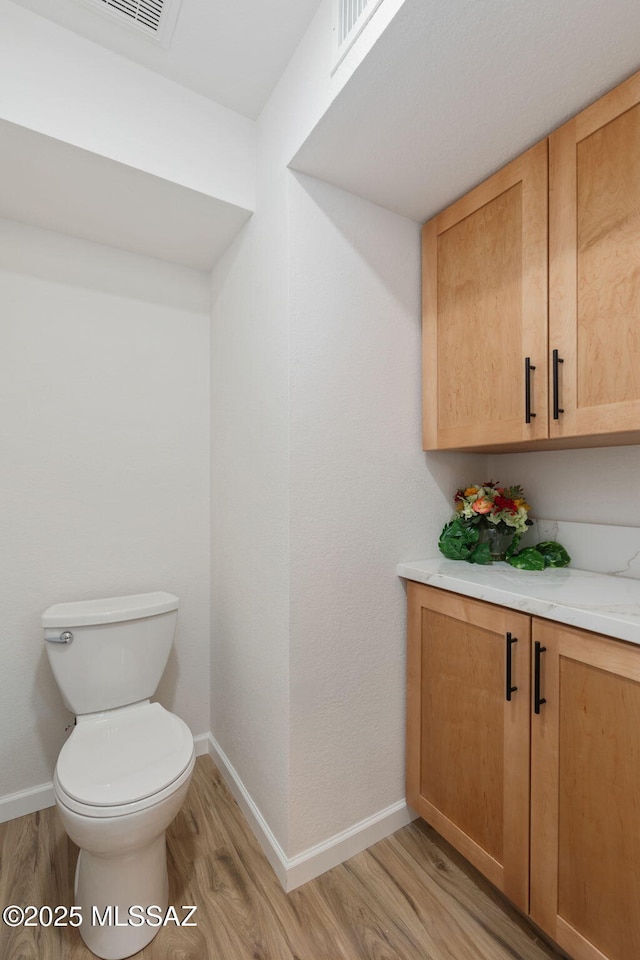 bathroom with visible vents, toilet, baseboards, and wood finished floors