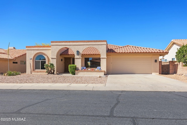 mediterranean / spanish home with a garage, concrete driveway, a tiled roof, and stucco siding