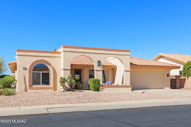 mediterranean / spanish house with a tile roof, driveway, an attached garage, and stucco siding