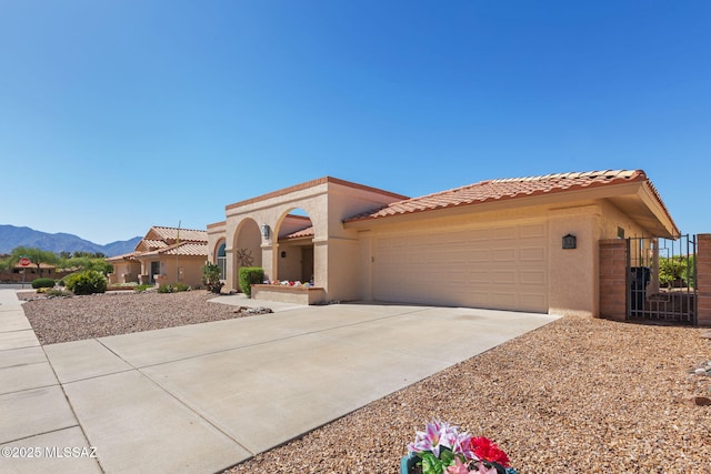 mediterranean / spanish-style house with driveway, a tile roof, a mountain view, and stucco siding