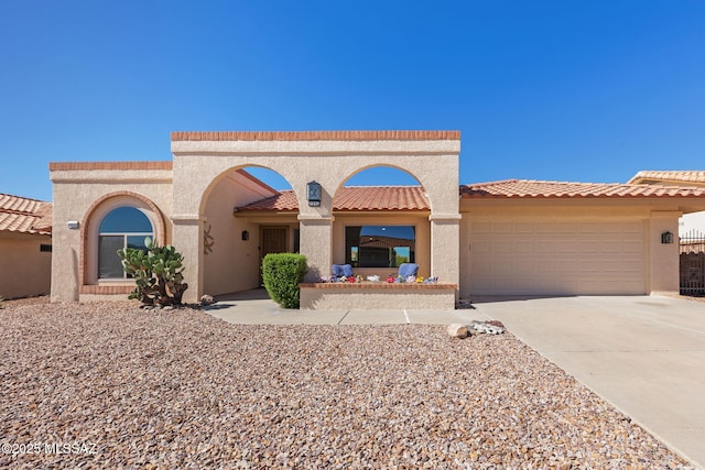 mediterranean / spanish-style home featuring driveway, an attached garage, a tiled roof, and stucco siding