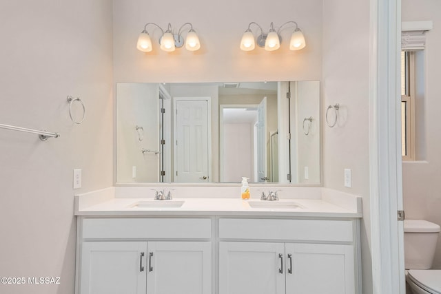 full bathroom with double vanity, a sink, and toilet