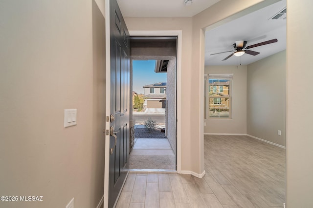 entryway with light wood-type flooring, visible vents, ceiling fan, and baseboards