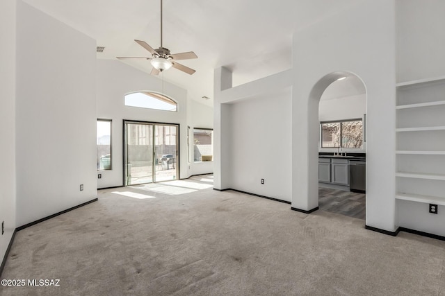 unfurnished living room featuring ceiling fan, sink, light colored carpet, and high vaulted ceiling