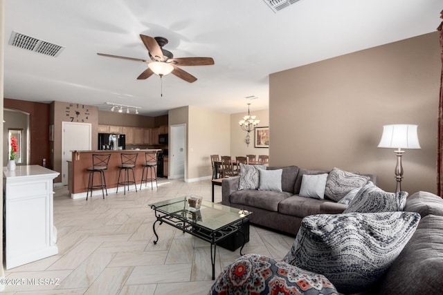 living room featuring ceiling fan with notable chandelier, rail lighting, and light parquet flooring