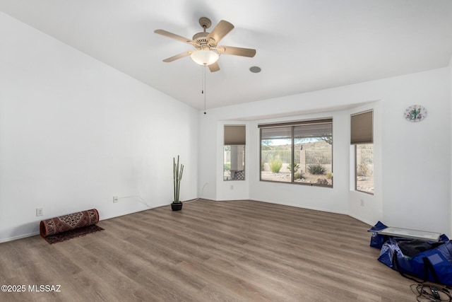 empty room with hardwood / wood-style flooring, ceiling fan, and vaulted ceiling