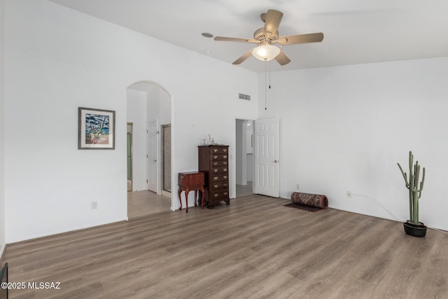 empty room featuring ceiling fan, a high ceiling, and light wood-type flooring