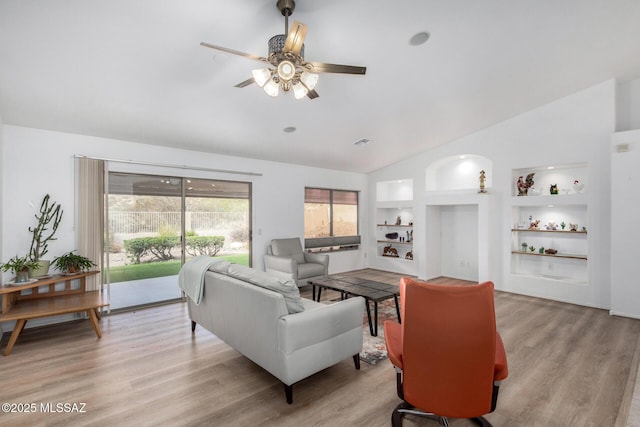 living room featuring ceiling fan, vaulted ceiling, built in features, and light wood-type flooring