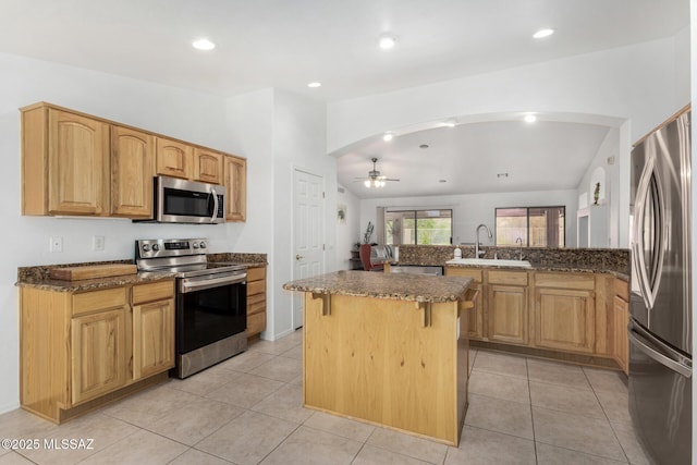 kitchen with a kitchen island, appliances with stainless steel finishes, sink, a kitchen bar, and light tile patterned floors