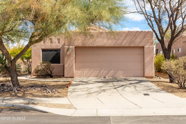 pueblo-style house featuring concrete driveway, an attached garage, and stucco siding