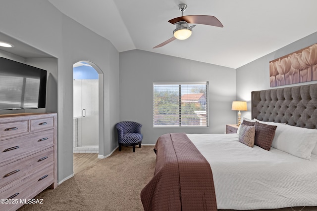 carpeted bedroom featuring arched walkways, ceiling fan, lofted ceiling, connected bathroom, and baseboards