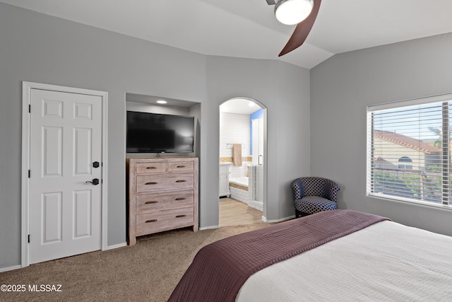 bedroom with lofted ceiling, arched walkways, ensuite bathroom, carpet flooring, and baseboards