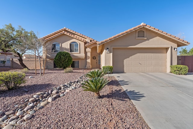 mediterranean / spanish home featuring driveway, an attached garage, fence, and stucco siding