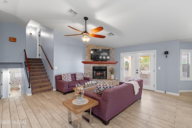 living room featuring stairway, visible vents, vaulted ceiling, and light wood-style flooring