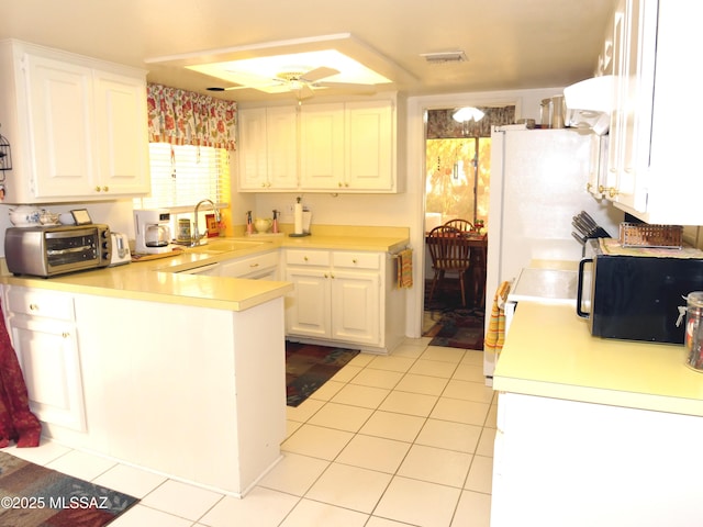 kitchen featuring white cabinets, a toaster, light countertops, black microwave, and a peninsula