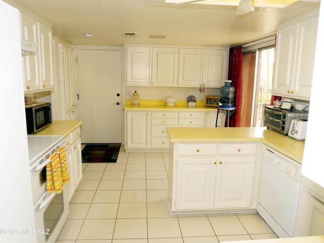 kitchen featuring a peninsula, visible vents, white appliances, and light countertops