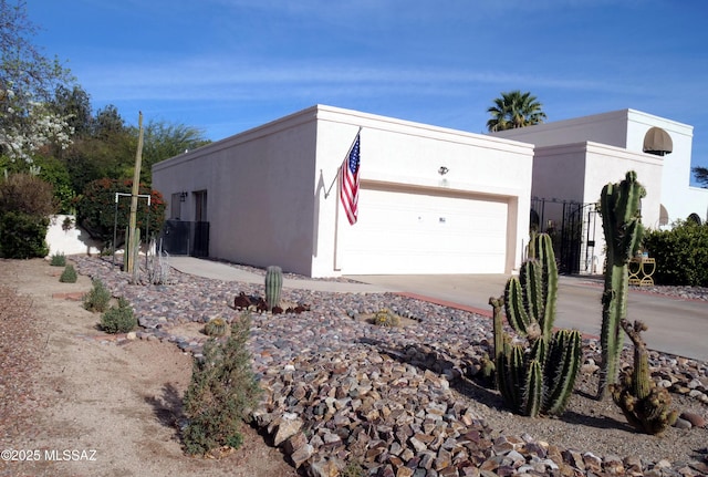view of side of home with an attached garage, concrete driveway, and stucco siding