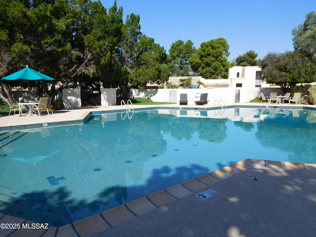 community pool with fence and a patio