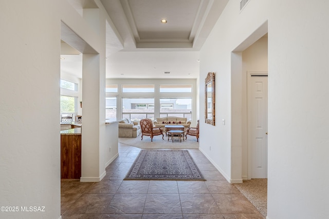 foyer entrance with a raised ceiling, visible vents, a towering ceiling, and baseboards