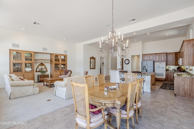 dining area featuring light carpet, light tile patterned floors, a high ceiling, and visible vents