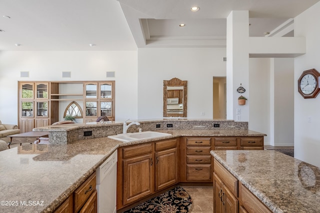 kitchen with dishwasher, open floor plan, light stone countertops, a sink, and recessed lighting