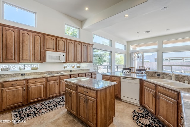 kitchen featuring brown cabinets, white appliances, visible vents, and a sink