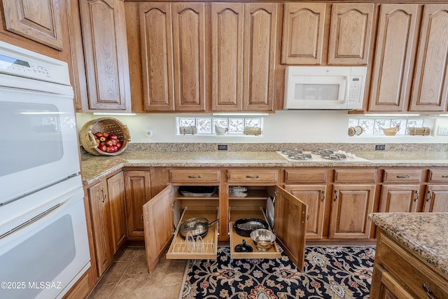 kitchen with light stone countertops, white appliances, and light tile patterned floors