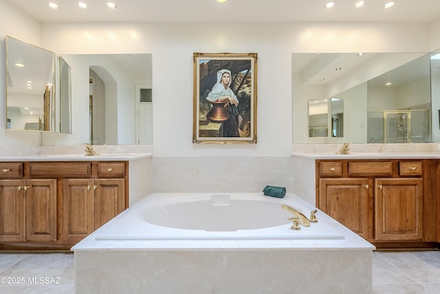 bathroom featuring tile patterned flooring, two vanities, and a bath