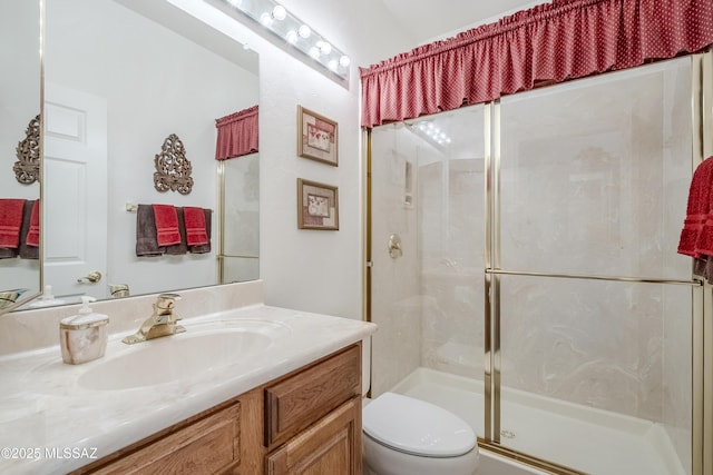 bathroom with a stall shower, vanity, and toilet