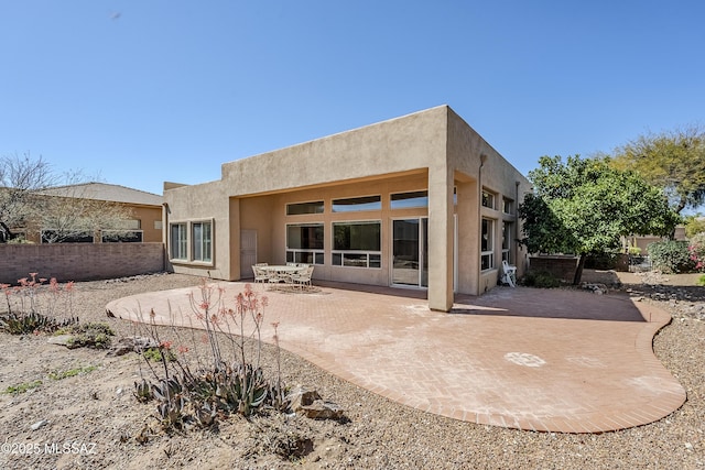 rear view of property with a patio area, fence, and stucco siding