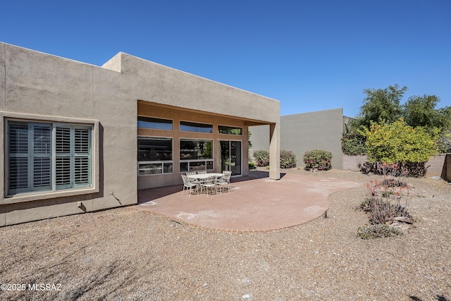 rear view of house featuring a patio area and stucco siding