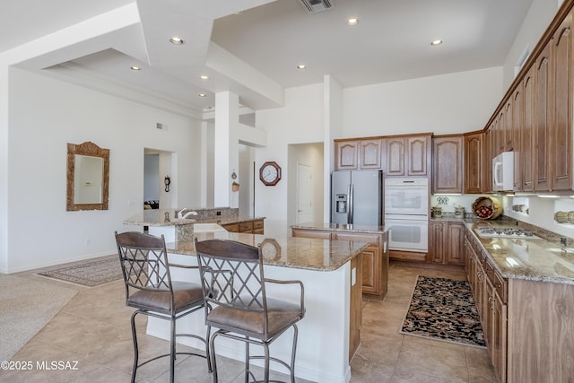 kitchen with white appliances, a kitchen bar, and a high ceiling