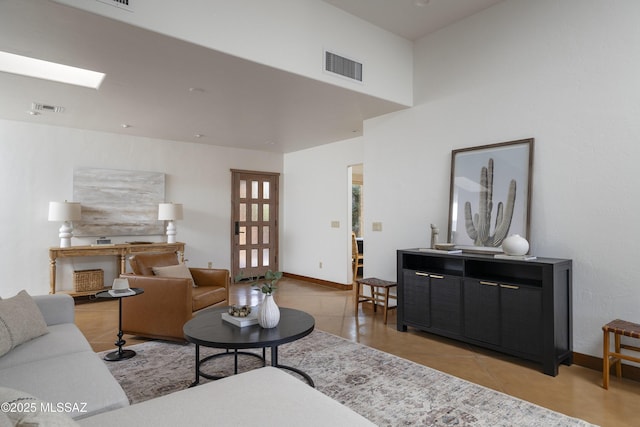 living area featuring light tile patterned floors, visible vents, and baseboards