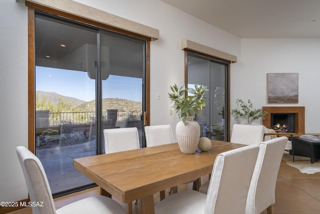 tiled dining room featuring a mountain view and a lit fireplace