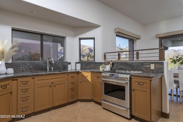 kitchen featuring dark stone countertops, stainless steel electric range, tasteful backsplash, and a sink