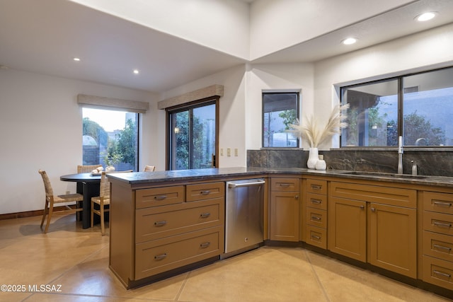 kitchen with backsplash, dark stone counters, recessed lighting, a peninsula, and a sink