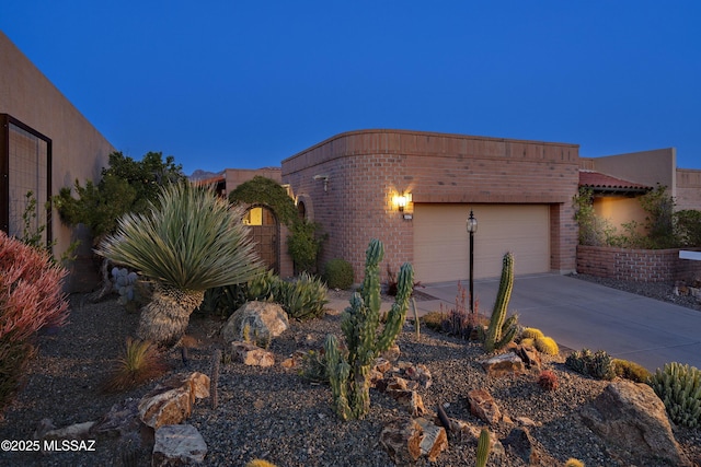 view of side of property featuring brick siding, concrete driveway, and a garage