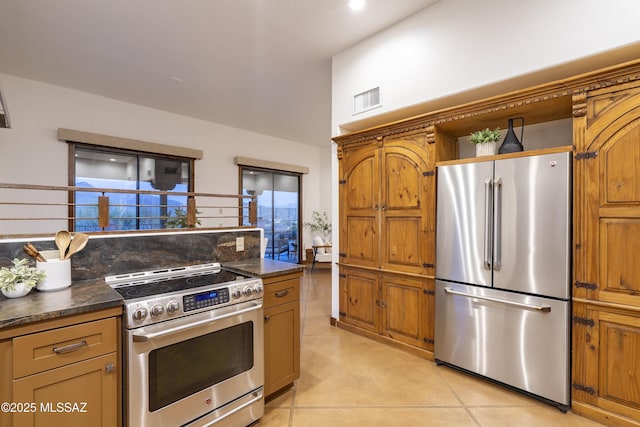 kitchen with light tile patterned floors, visible vents, dark countertops, and appliances with stainless steel finishes