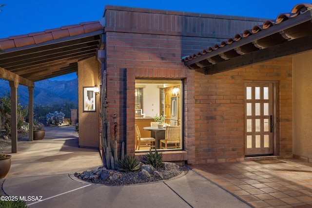 doorway to property featuring a mountain view, brick siding, and a patio area