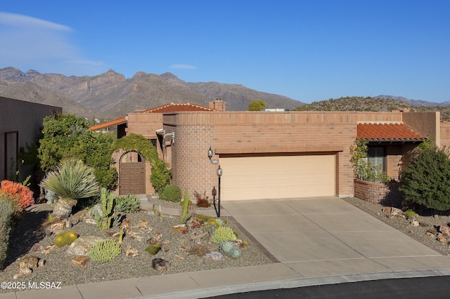 view of front of property featuring a garage, a mountain view, driveway, and a tile roof