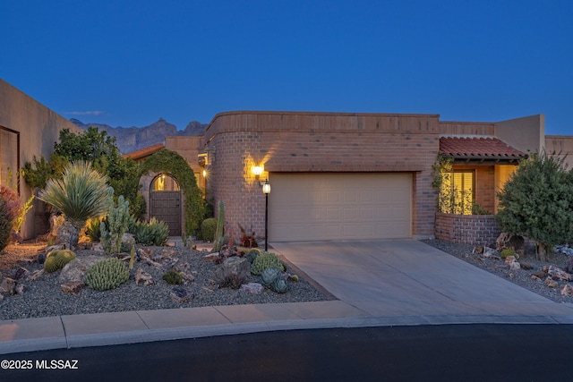 view of front of home featuring a garage, brick siding, concrete driveway, and a mountain view