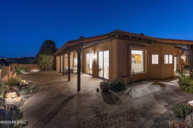 view of side of property with a patio, a tiled roof, and fence