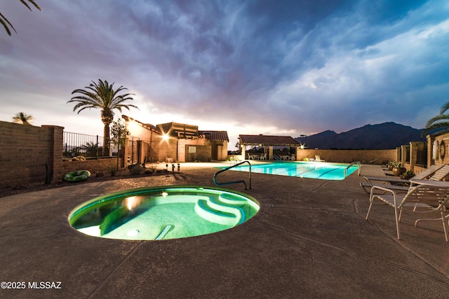 community pool with a patio area, a hot tub, and fence