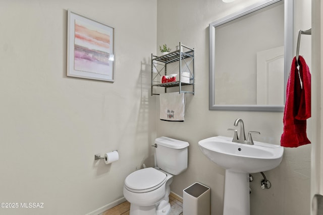 bathroom with tile patterned flooring, baseboards, and toilet