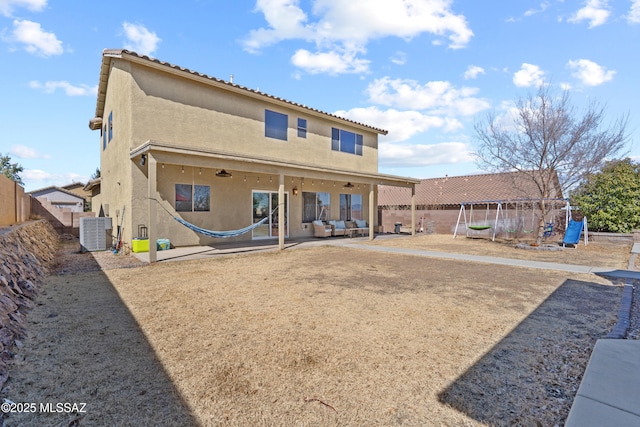 back of property with fence, cooling unit, a patio area, a playground, and stucco siding