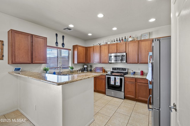 kitchen featuring light tile patterned floors, a sink, visible vents, appliances with stainless steel finishes, and brown cabinetry