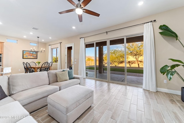 living room featuring ceiling fan with notable chandelier and light hardwood / wood-style flooring