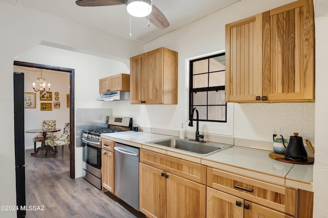 kitchen featuring dark wood-style floors, tasteful backsplash, appliances with stainless steel finishes, a sink, and under cabinet range hood